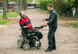 Man in wheelchair joking with a man standing in front of him