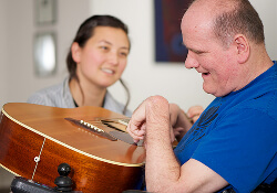 Man playing guitar with lady looking on