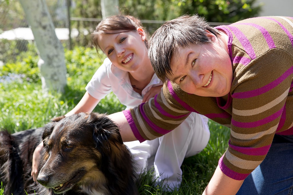 Two women and a dog on a field