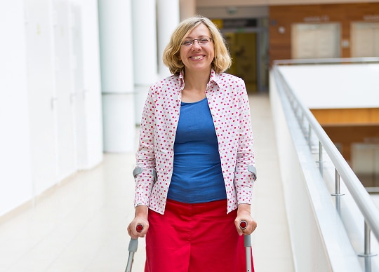 A woman on crutches walking, smiling