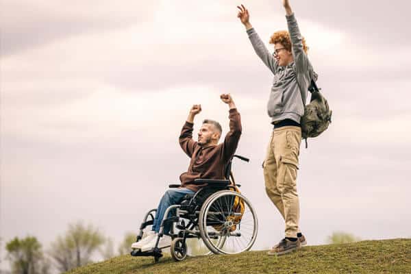 Two men cheering and smiling. One man is in a wheelchair.