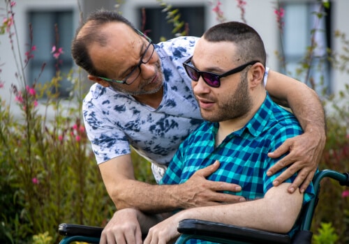 A man with his arms around another who is in a wheelchair