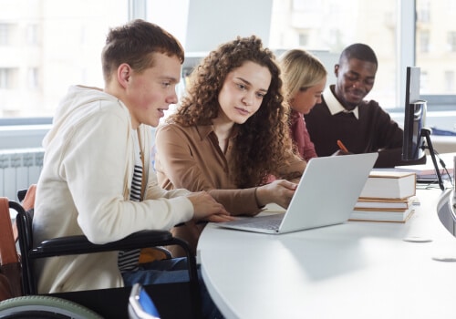 Two students in a classroom looking at a laptop
