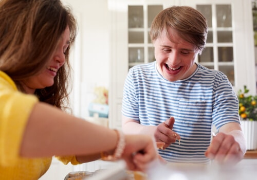 Two friends smiling as they sit at a table doing activities