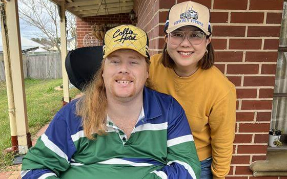 A man in a wheelchair smiling at his support worker