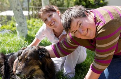 Two women and a dog on a field