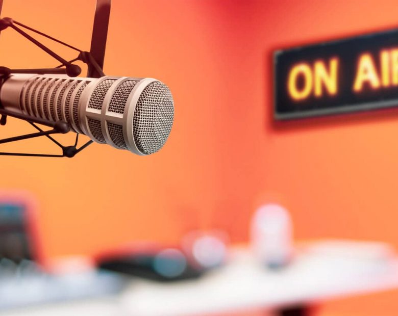 A photo of a recording studio showing a microphone and an 'on air' light up sign