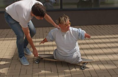 Photo of a man with no legs riding on a skateboard with assistance