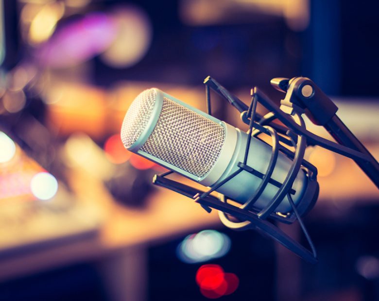 Microphone in a professional recording or radio studio, equipment in the blurry background